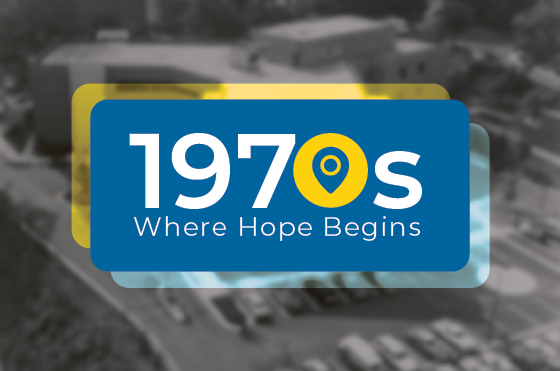 A graphic with the text "1970s Where Hope Begins" overlays a blurred, grayscale aerial image of a building and parking lot in the background.